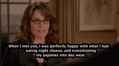 a woman wearing glasses is talking to a man in a suit while eating night cheese