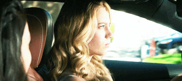 a woman is sitting in the back seat of a car talking to another person
