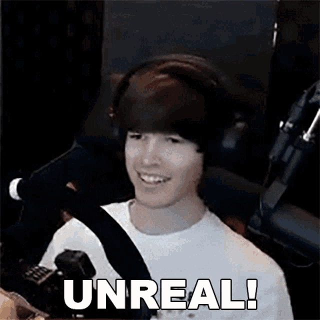 a young man wearing headphones is sitting in front of a microphone with the words unreal written below him .