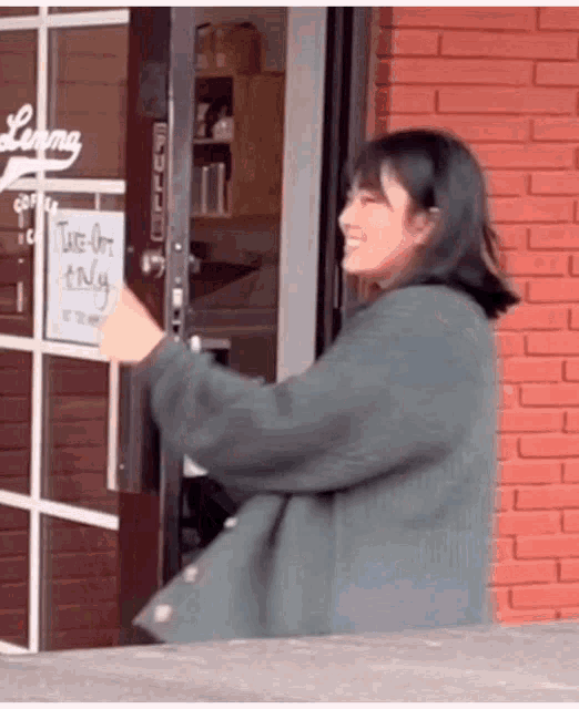 a woman is standing in front of a store with a take out only sign on the door .
