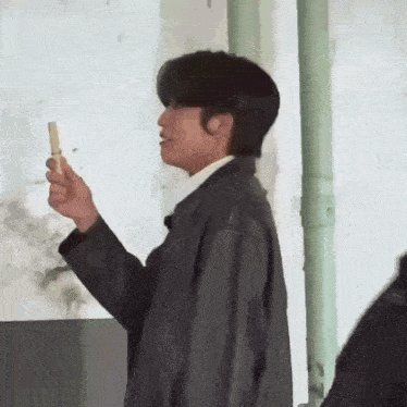 a man in a black jacket is holding a stick in his hand and looking at it .