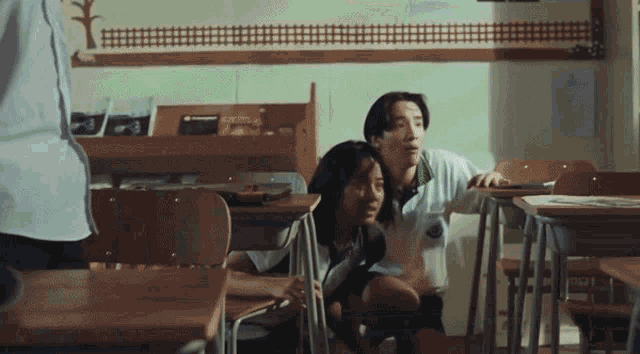 a man and a woman are sitting in a classroom with a sign that says ' a ' on it