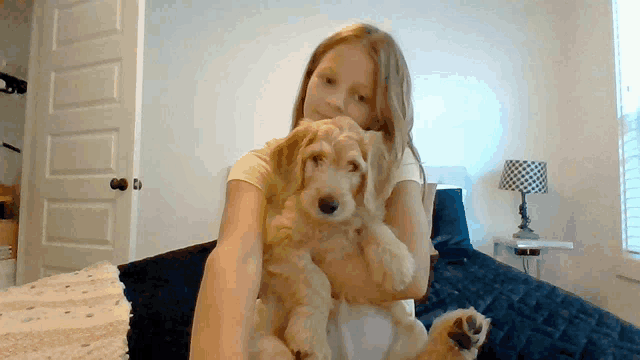 a girl is holding a puppy in her arms
