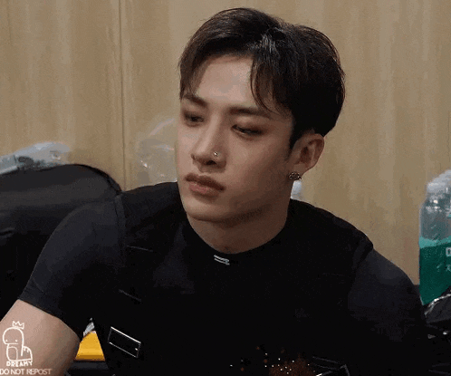 a young man with a nose ring and earrings is sitting in a room .