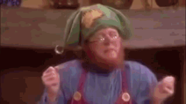 a man with a beard and glasses is wearing a green hat and apron