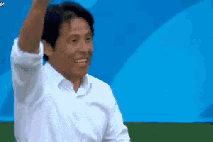 a man in a white shirt is raising his arm in the air