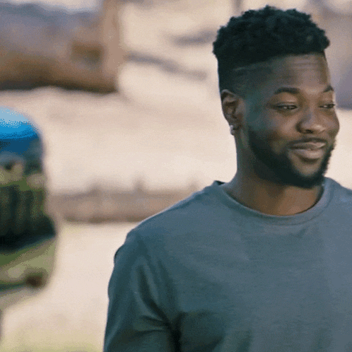 a man with a beard is wearing a grey shirt and smiling