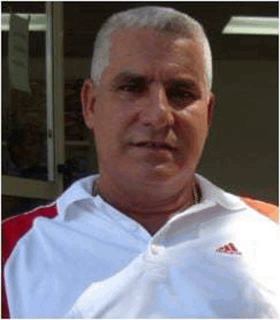 a man wearing a white and red adidas shirt is standing in front of a store .