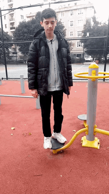 a boy in a black jacket is standing next to a yellow and silver device