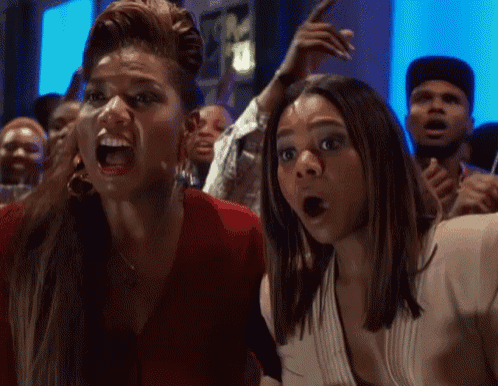 two women are screaming in a crowd and one has her mouth open