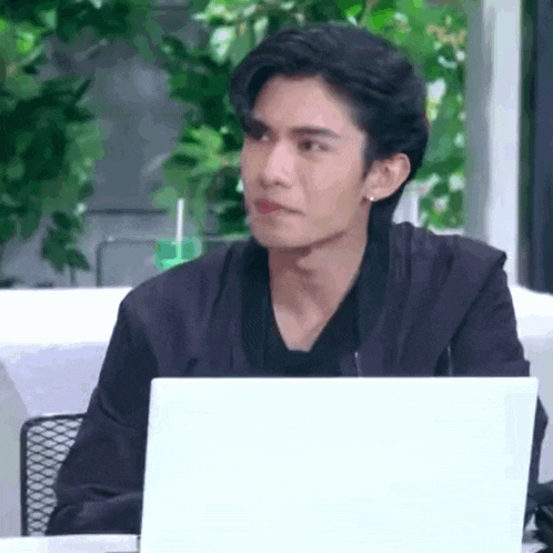 a young man is sitting at a table with a laptop computer .
