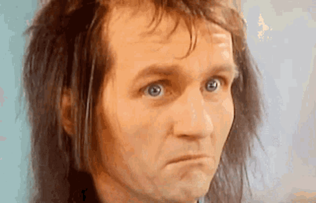 a close up of a man with long hair making a face
