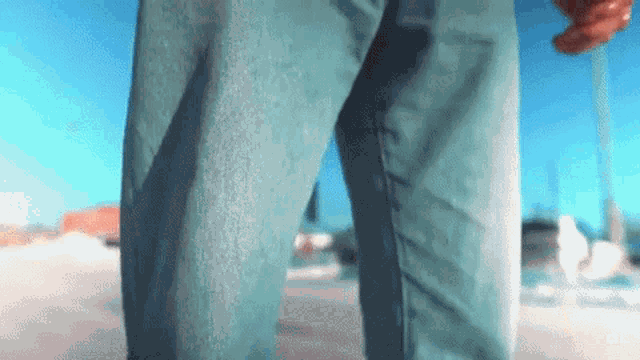 a person wearing blue jeans is standing on a street .