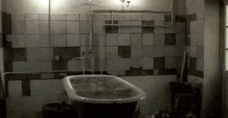 a bathtub in a bathroom with a lot of tiles and pipes .