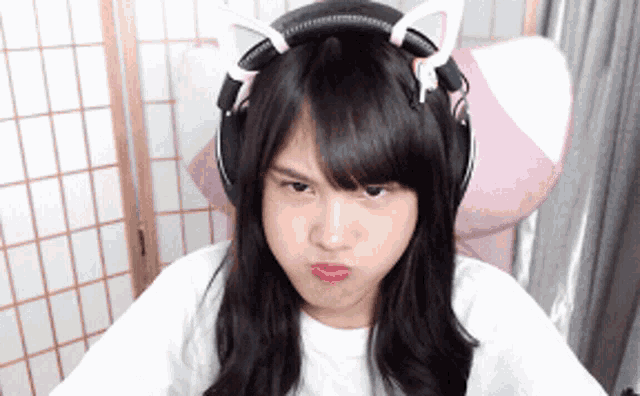 a girl wearing headphones with cat ears on her head makes a funny face