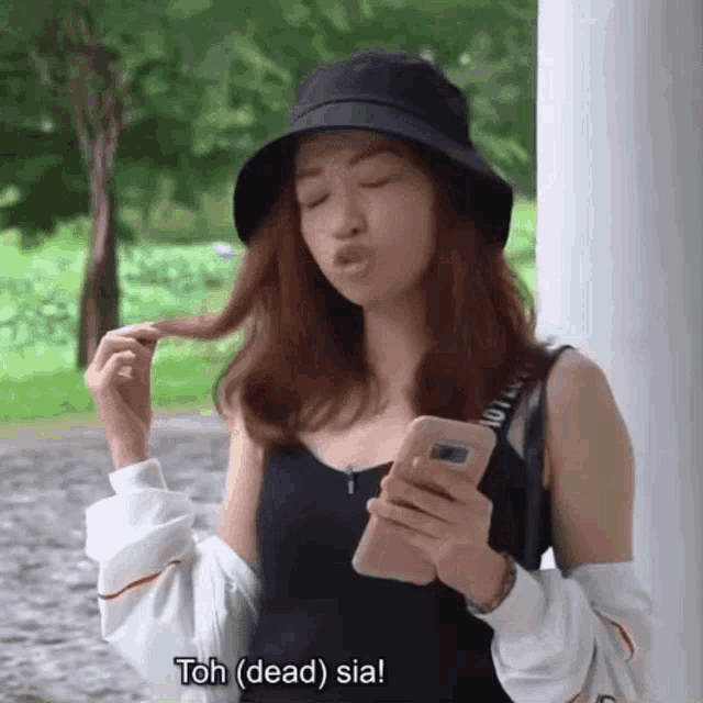 a woman wearing a black hat is holding a cell phone .