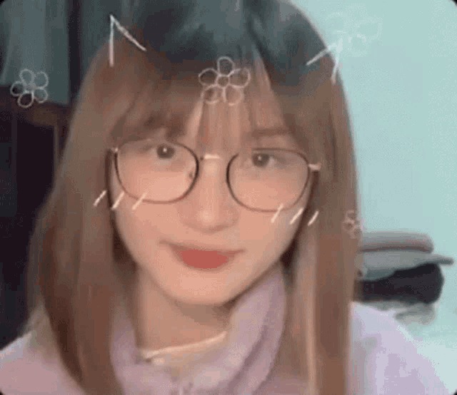 a girl wearing glasses and a purple sweater is looking at the camera and smiling .