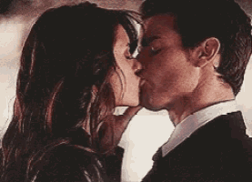 a man and a woman are kissing and the woman is whispering something into the man 's ear .