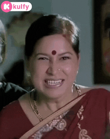 a woman in a red saree with a red dot on her forehead is smiling