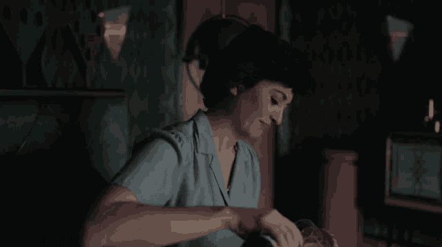 a woman in a blue shirt is sitting at a table holding a glass of beer
