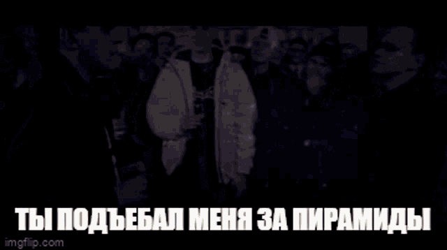 a man in a white jacket stands in front of a crowd with a caption in russian
