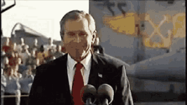 a man in a suit and tie is standing in front of a microphone .