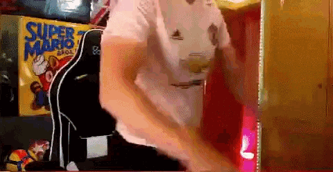 a man in a white shirt is dancing in front of a sign that says super mario