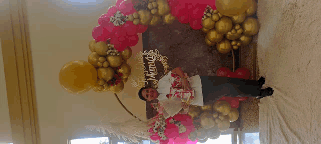 a man stands in front of a display of balloons with a sign that says dia mama
