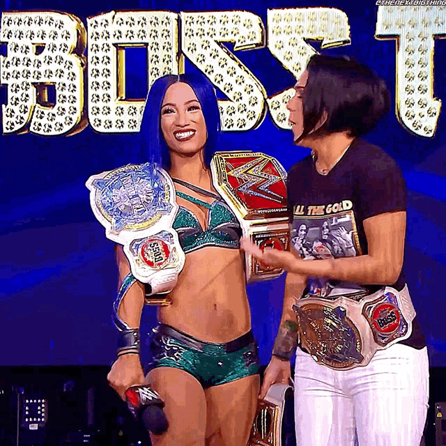a woman in a black shirt that says all the gold stands next to another woman