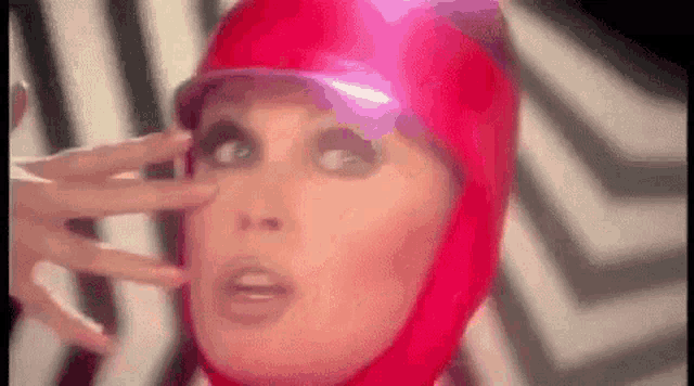 a close up of a woman wearing a red helmet with a purple visor .