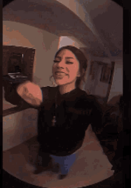 a girl in a black sweatshirt is dancing in front of a mirror and making a funny face