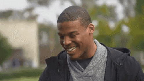 a man in a black jacket and grey scarf is smiling .