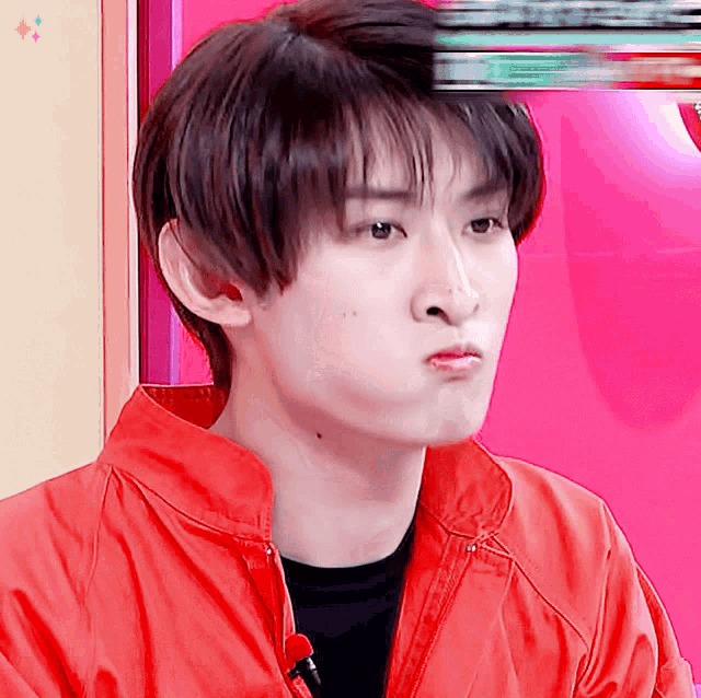 a young man wearing a red jacket making a funny face