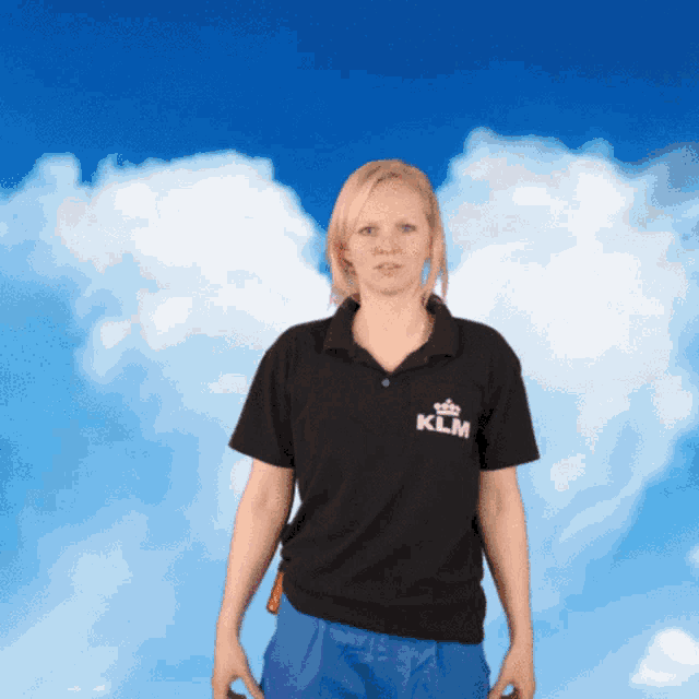 a woman wearing a black klm polo shirt stands in front of a blue sky