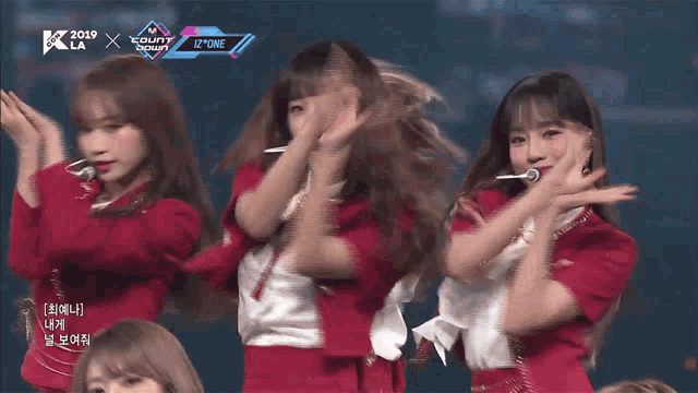 a group of girls are performing on a stage with a sign that says izone on it