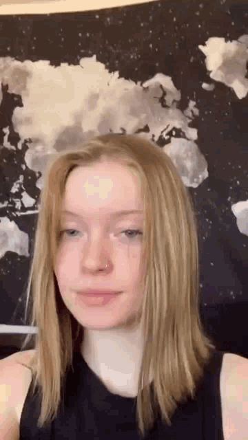 the girl is wearing a black tank top and has a nose ring .