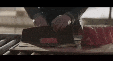 a person is cutting meat on a cutting board with a knife .