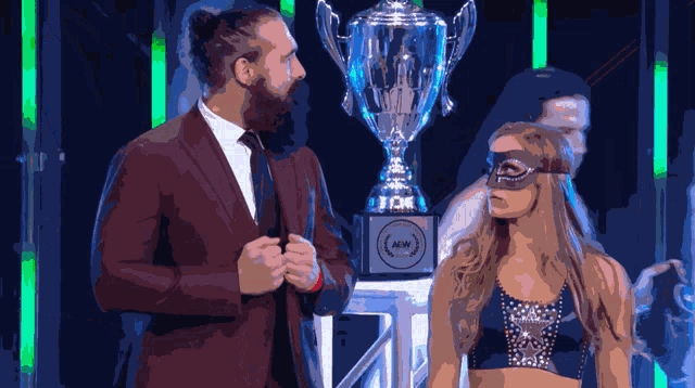 a man and a woman are standing next to a trophy that says new