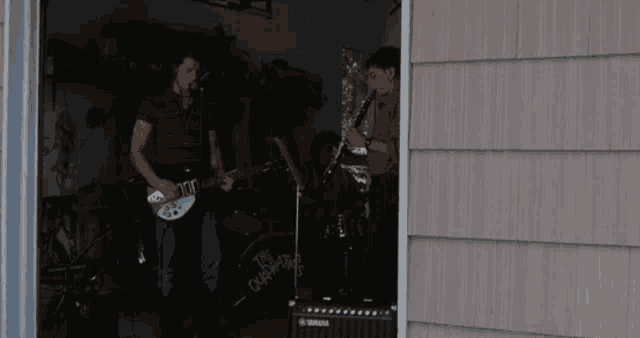 a man playing a guitar next to a man playing a saxophone in front of a drum set that says the champions