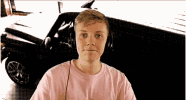 a young man wearing headphones stands in front of a black car