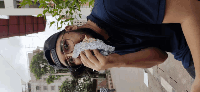 a man wearing glasses and a hat is eating a piece of food