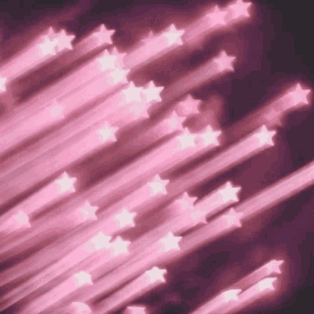 a bunch of pink stars are flying in the night sky .