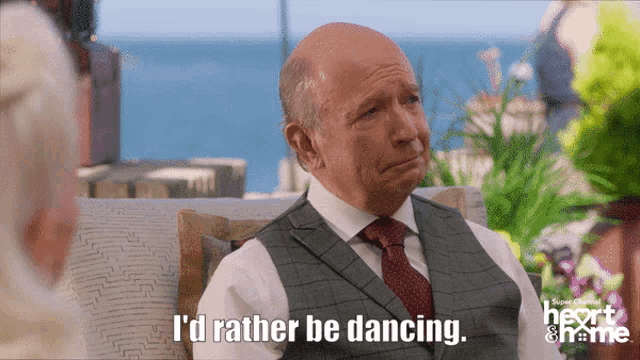 a man in a suit and tie says " i 'd rather be dancing " while sitting on a couch