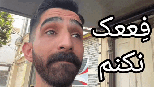 a man with a beard and mustache is standing in front of a building with a sign that says ' aa '