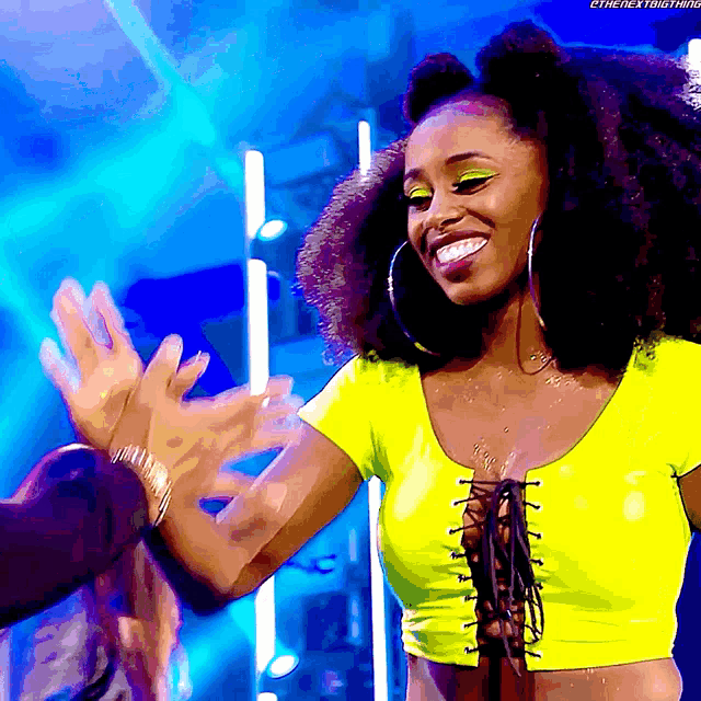 a woman in a neon yellow crop top is smiling