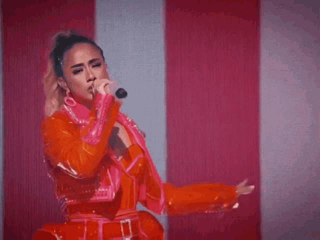 a woman singing into a microphone with a red and white striped background