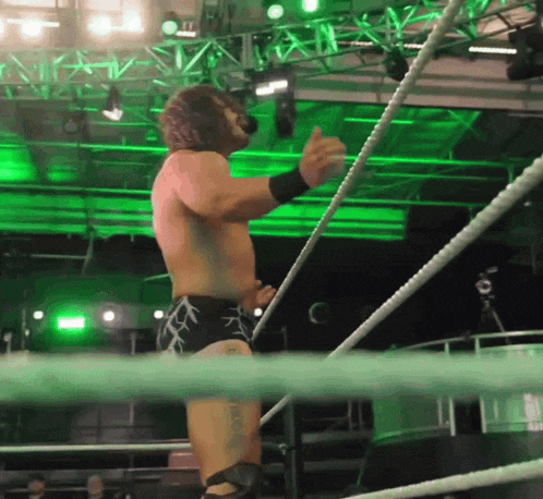a wrestler with a tattoo on his leg stands in a wrestling ring