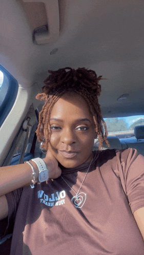 a woman wearing a mojo trash hut t-shirt is sitting in a car