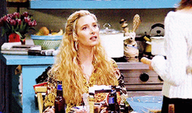 a blonde woman sitting at a table with bottles of alcohol