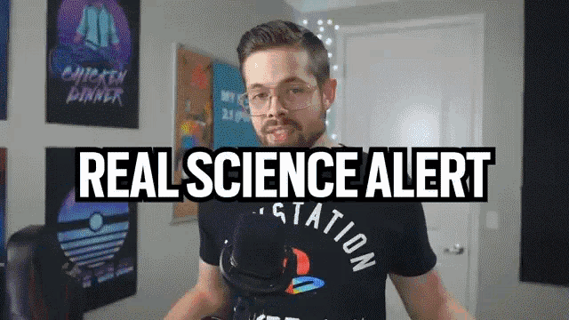 a man wearing a playstation shirt stands in front of a sign that says " real science alert "